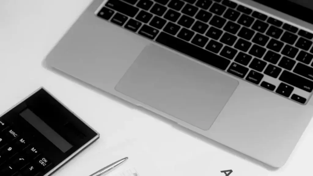 Ordinateur portable et calculatrice posés sur des documents financiers, illustration du calcul du budget d'une DSI externalisée pour une PME